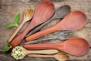 Top view of rustic wooden kitchen utensils and small flowers on a textured table.